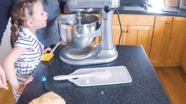 Adım adım. Anne ve kızı mutfakta şekerli kurabiye pişirme.