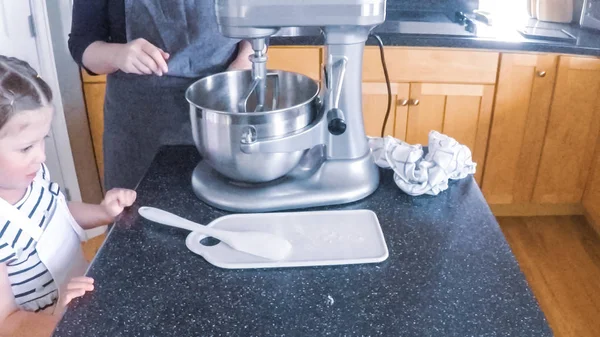 Adım adım. Anne ve kızı mutfakta şekerli kurabiye pişirme.