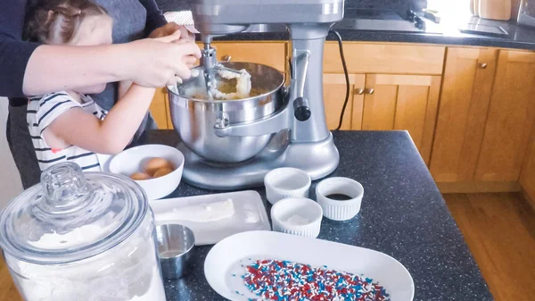 Adım adım. Anne ve kızı mutfakta şekerli kurabiye pişirme.