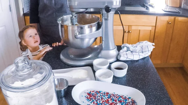 Adım adım. Anne ve kızı mutfakta şekerli kurabiye pişirme.