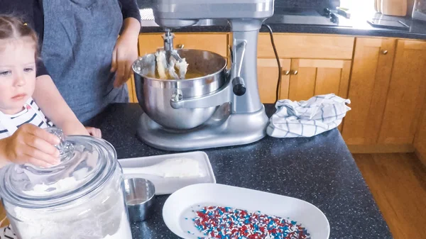 Adım adım. Anne ve kızı mutfakta şekerli kurabiye pişirme.