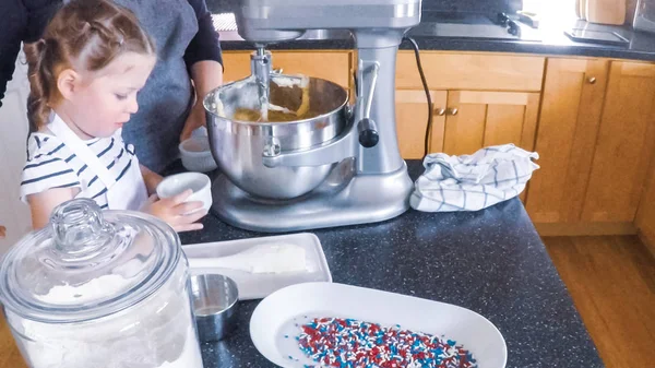 Adım adım. Anne ve kızı mutfakta şekerli kurabiye pişirme.