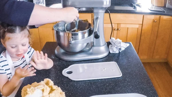 Adım adım. Anne ve kızı mutfakta şekerli kurabiye pişirme.