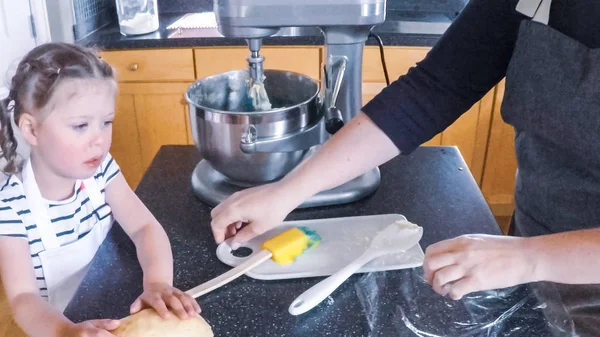 Adım adım. Anne ve kızı mutfakta şekerli kurabiye pişirme.