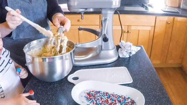 Adım adım. Anne ve kızı mutfakta şekerli kurabiye pişirme.