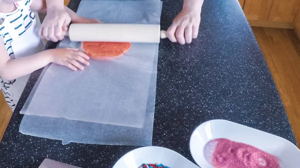 Adım adım. Anne ve kızı mutfakta şekerli kurabiye pişirme.