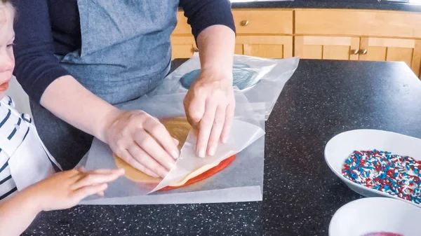 Adım adım. Anne ve kızı mutfakta şekerli kurabiye pişirme.