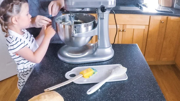 Adım adım. Anne ve kızı mutfakta şekerli kurabiye pişirme.