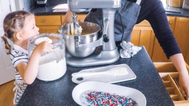 Adım adım. Anne ve kızı mutfakta şekerli kurabiye pişirme.