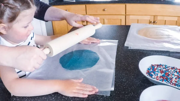 Adım adım. Anne ve kızı mutfakta şekerli kurabiye pişirme.