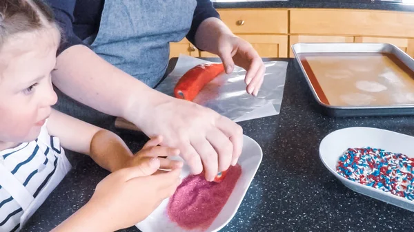 Adım adım. Anne ve kızı mutfakta şekerli kurabiye pişirme.