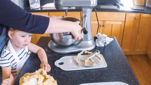 Adım adım. Anne ve kızı mutfakta şekerli kurabiye pişirme.