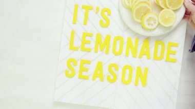 İçerisi limonata sezon ahşap işareti ile taze limon ağaç kesme tahtasında dilimlenmiş.
