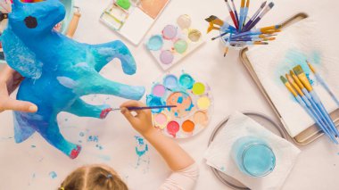 Adım adım. Resim kağıt mache unicorn mavi boya ile.