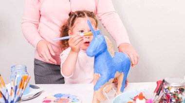 Anne ve kızı boyama kağıt mache unicorn mavi ile birlikte boya.
