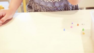 Çocuklar ellerine bilezik yapmak için renkli boncuk çekimi kapat