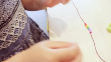 Çocuklar ellerine bilezik yapmak için renkli boncuk çekimi kapat