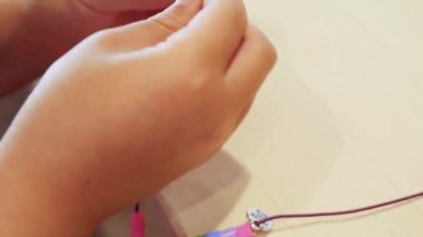 Çocuklar ellerine bilezik yapmak için renkli boncuk çekimi kapat