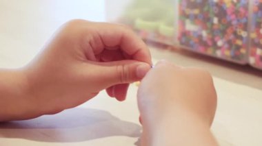 Çocuklar ellerine bilezik yapmak için renkli boncuk çekimi kapat