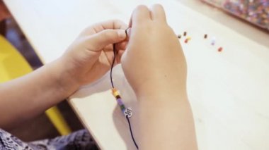 Çocuklar ellerine bilezik yapmak için renkli boncuk çekimi kapat