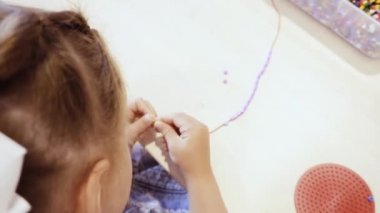 Çocuklar ellerine bilezik yapmak için renkli boncuk çekimi kapat