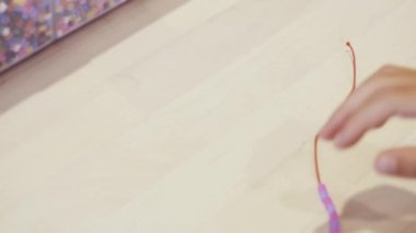 Çocuklar ellerine bilezik yapmak için renkli boncuk çekimi kapat