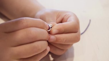 Çocuklar ellerine bilezik yapmak için renkli boncuk çekimi kapat