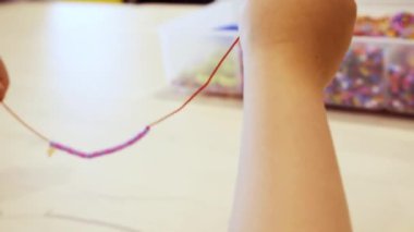 Çocuklar ellerine bilezik yapmak için renkli boncuk çekimi kapat