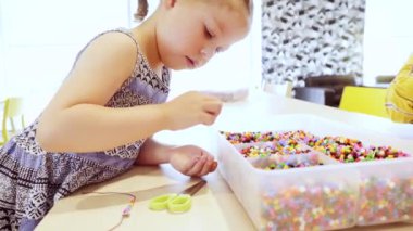 Küçük kız renkli çocuklar boncuk bilezik yapımı.