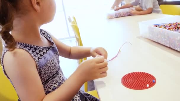 Kleines Mädchen Bastelt Armband Aus Bunten Kinderperlen — Stockvideo