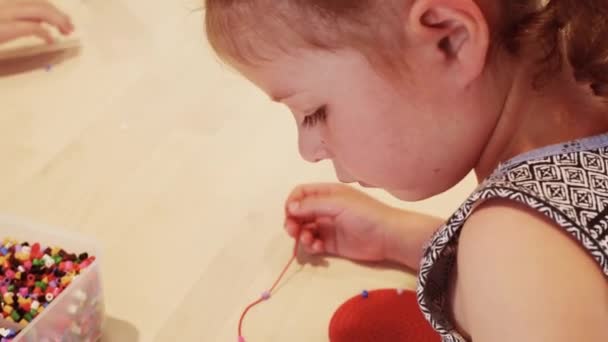 Κοντινό Πλάνο Του Χέρια Παιδιά Stringing Πολύχρωμες Χάντρες Κάνουν Βραχιόλι — Αρχείο Βίντεο