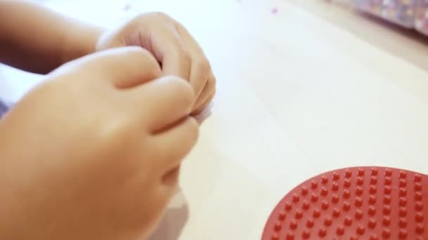 Kleines Mädchen Bastelt Muster Aus Bunten Perlen Auf Perlenbrett — Stockvideo