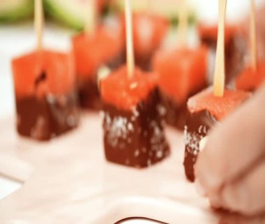 karpuz küpleri içinde eritilmiş çikolata ve deniz tuzu ve badem ile süsleme.