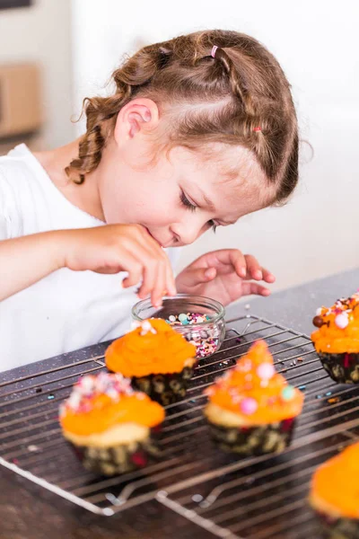 Menina Decorando Cereja Laranja Cupcakes Com Mistura Polvilhe — Fotografia de Stock