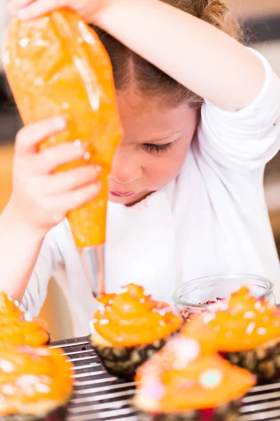 Little Girl Decorating Orange Icing Cupcakes Sprinkle Mix Stock Image
