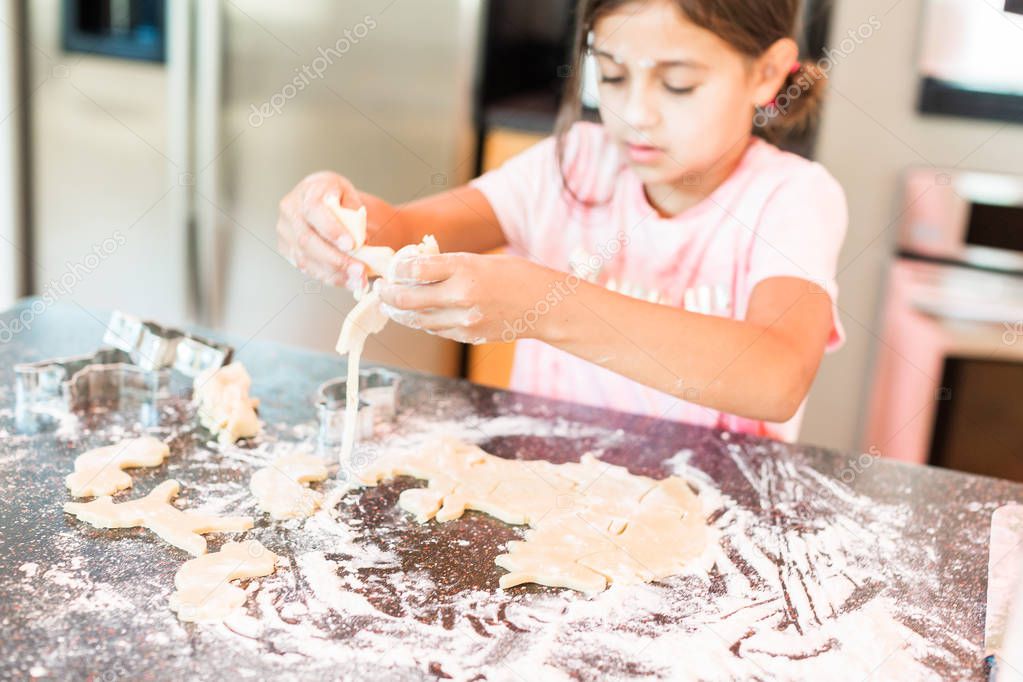 Little girl rolling out and cutting out unicorn sugar cookies.