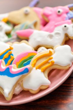 Pembe plaka üzerine Kraliyet krema ile çocuklar tarafından dekore edilmiş şekerli kurabiye şeklinde unicorn.