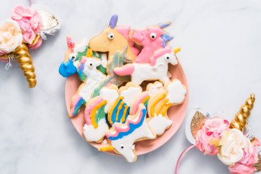 Pembe plaka üzerine Kraliyet krema ile çocuklar tarafından dekore edilmiş şekerli kurabiye şeklinde unicorn.