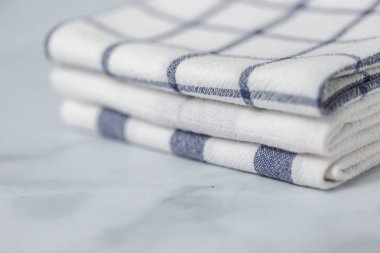 Mermer tezgahın üzerine katlanmış basit mavi desenli yeni mutfak havluları.