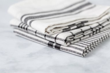 Mermer tezgahın üzerine katlanmış basit siyah desenli yeni mutfak havluları.