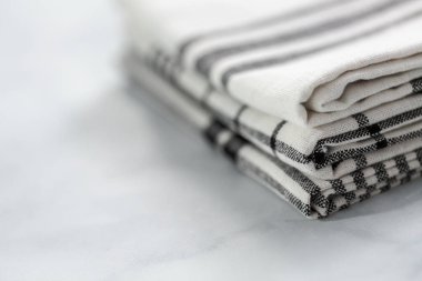 Mermer tezgahın üzerine katlanmış basit siyah desenli yeni mutfak havluları.