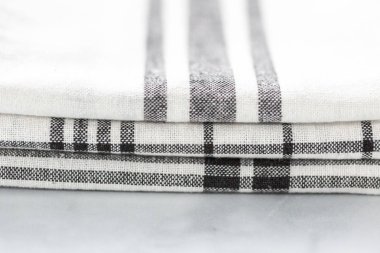 Mermer tezgahın üzerine katlanmış basit siyah desenli yeni mutfak havluları.