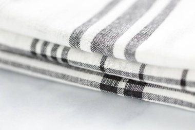 Mermer tezgahın üzerine katlanmış basit siyah desenli yeni mutfak havluları.