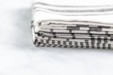 Mermer tezgahın üzerine katlanmış basit siyah desenli yeni mutfak havluları.