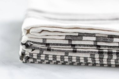 Mermer tezgahın üzerine katlanmış basit siyah desenli yeni mutfak havluları.