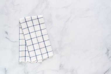 Mermer tezgahın üzerine katlanmış basit mavi desenli yeni mutfak havluları.