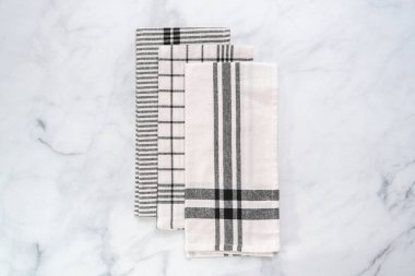 Mermer tezgahın üzerine katlanmış basit siyah desenli yeni mutfak havluları.