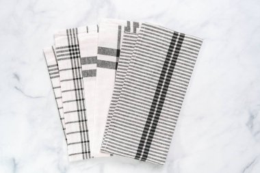 Mermer tezgahın üzerine katlanmış basit siyah desenli yeni mutfak havluları.