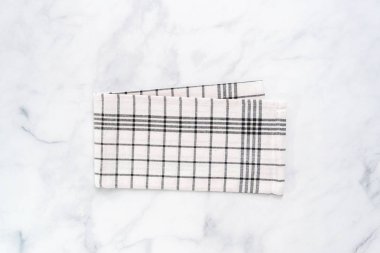 Mermer tezgahın üzerine katlanmış basit siyah desenli yeni mutfak havluları.