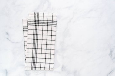 Mermer tezgahın üzerine katlanmış basit siyah desenli yeni mutfak havluları.